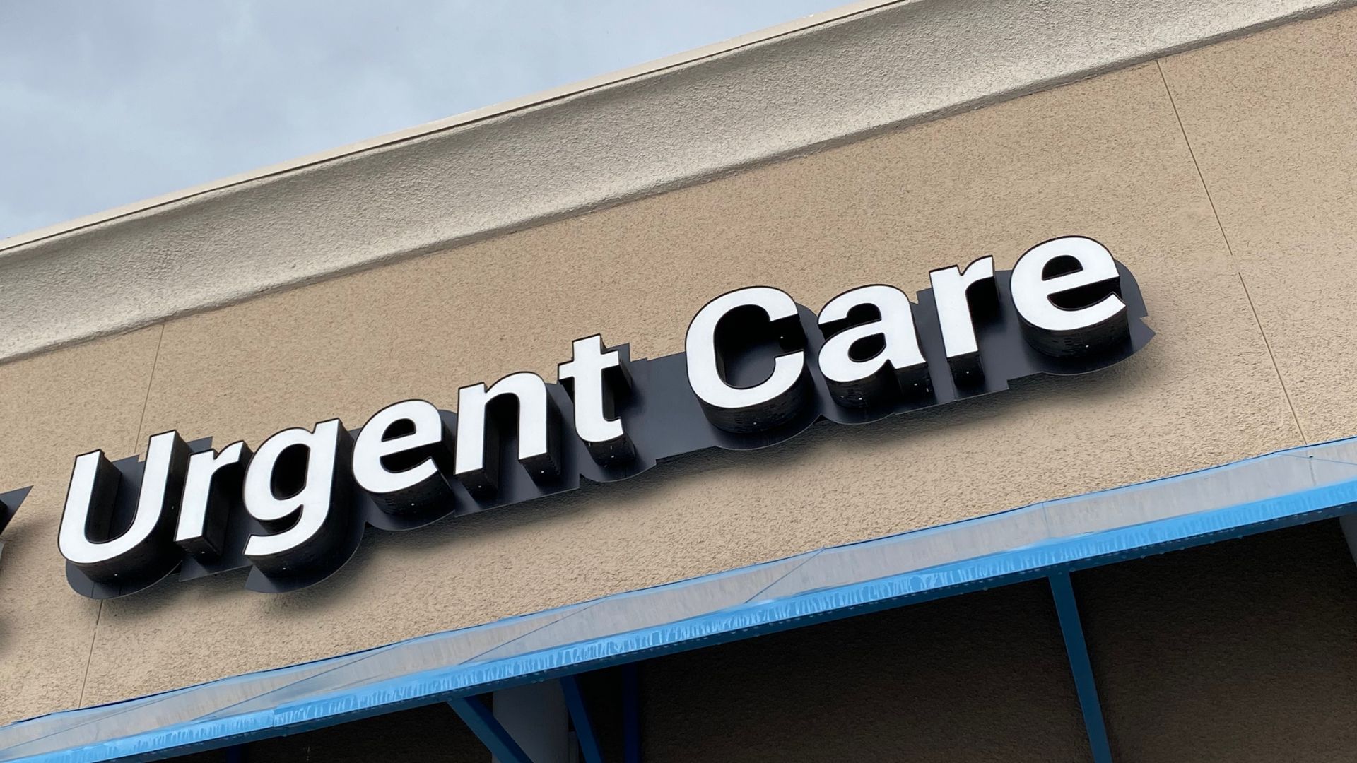 Large white and black Urgent Care sign on beige building exterior