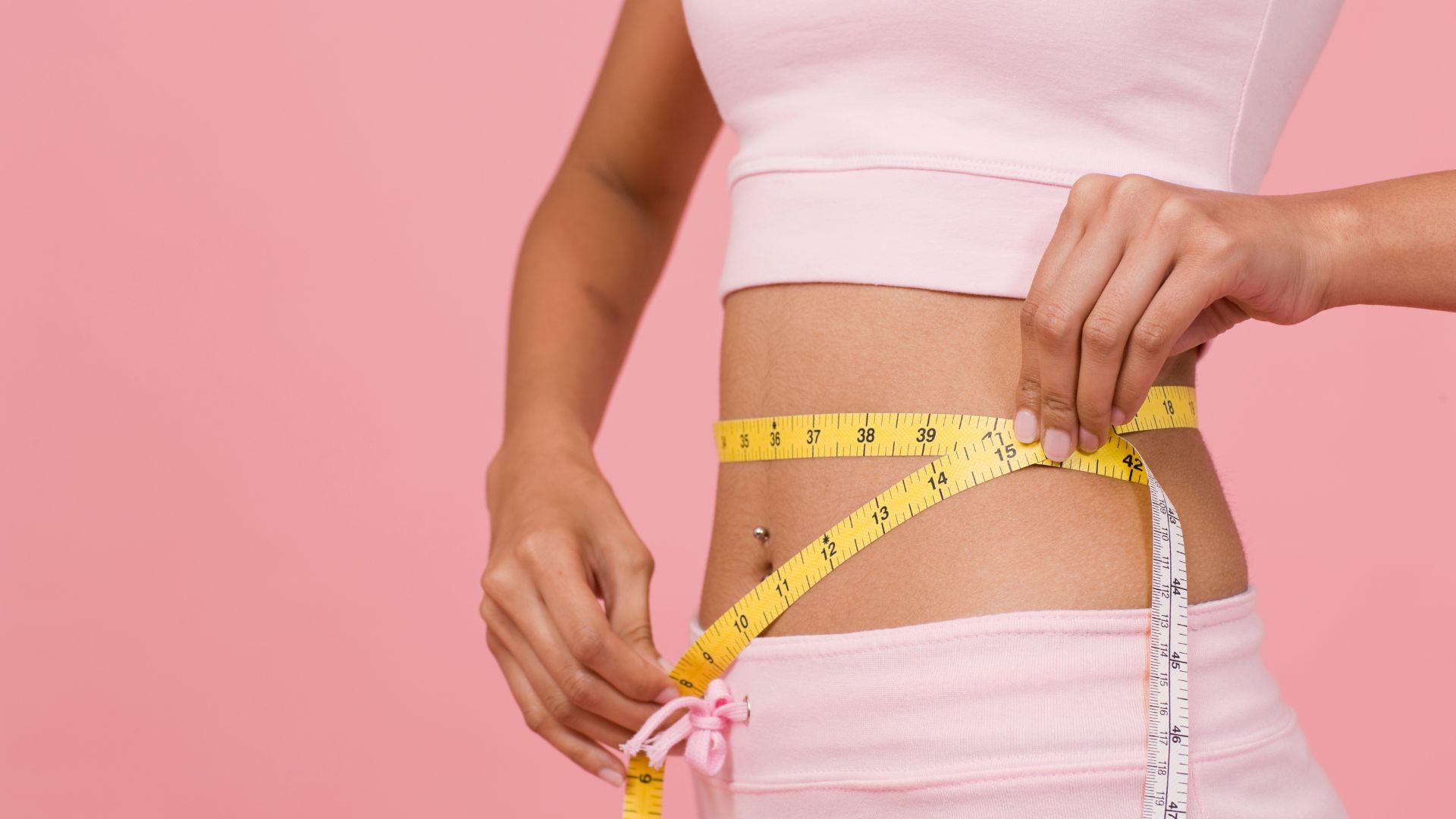 Person measuring waist with yellow and white measuring tape