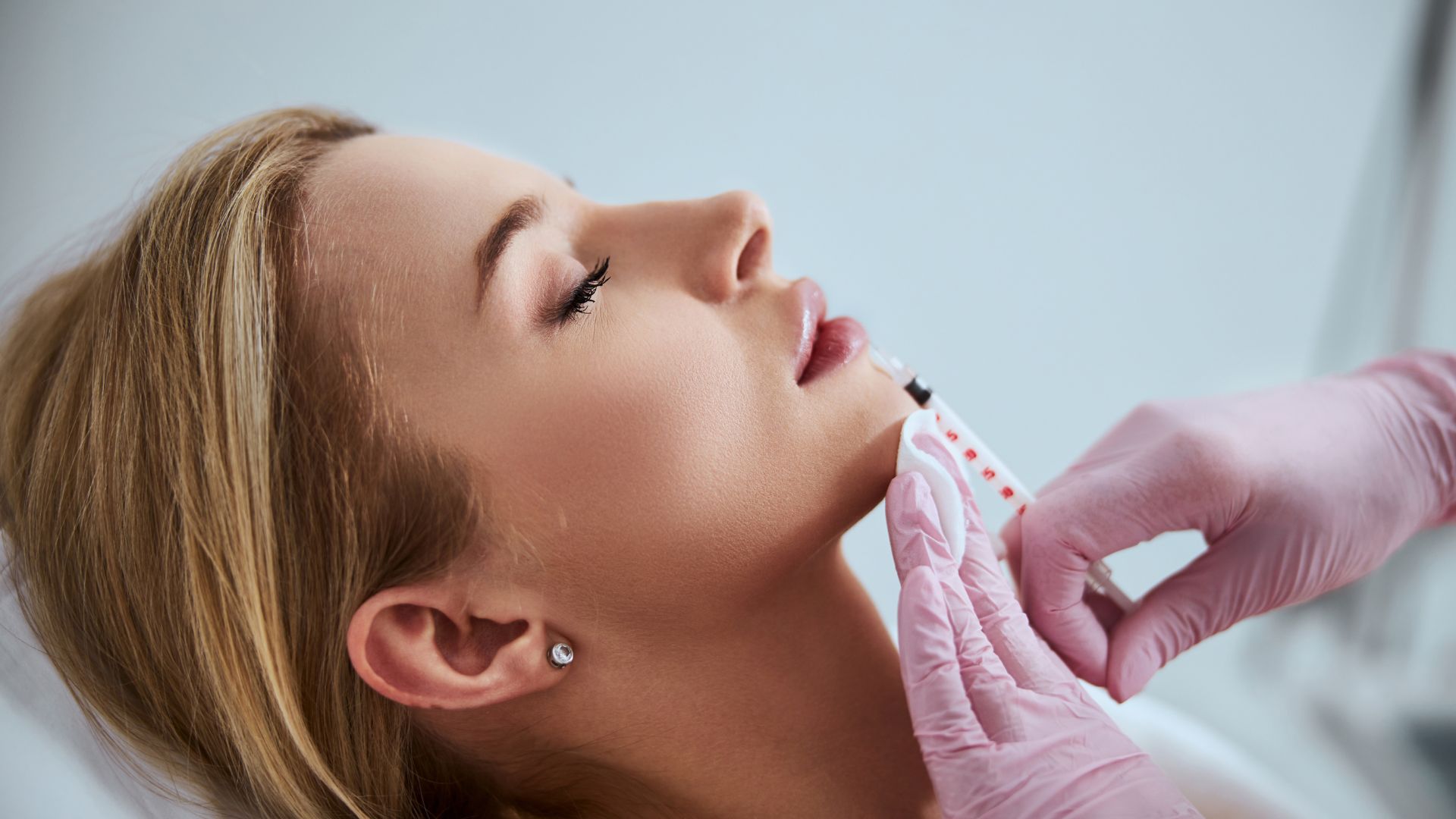 Cosmetic procedure with gloved hands injecting patient's face