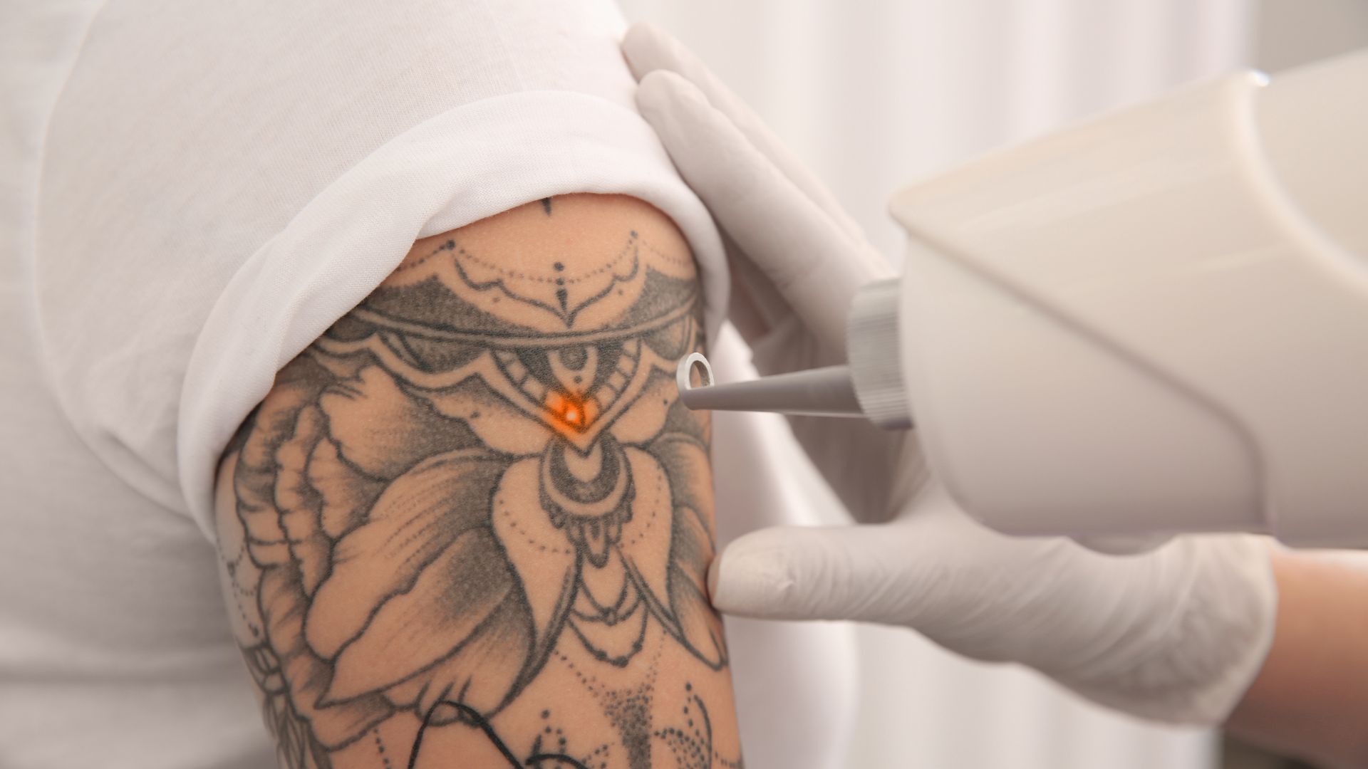 Tattoo artist in gloves working on intricate mandala-style shoulder tattoo