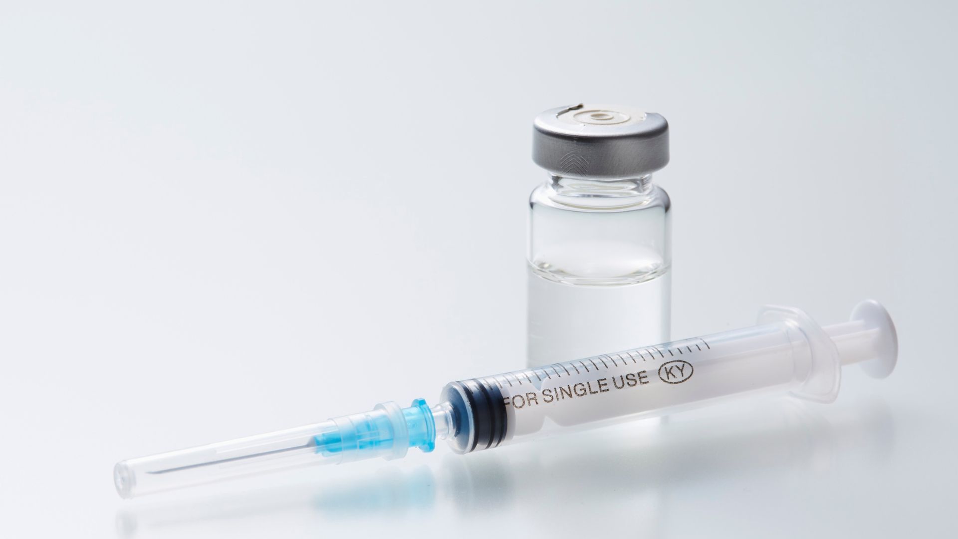 Medical syringe and vaccine vial for single use on white background